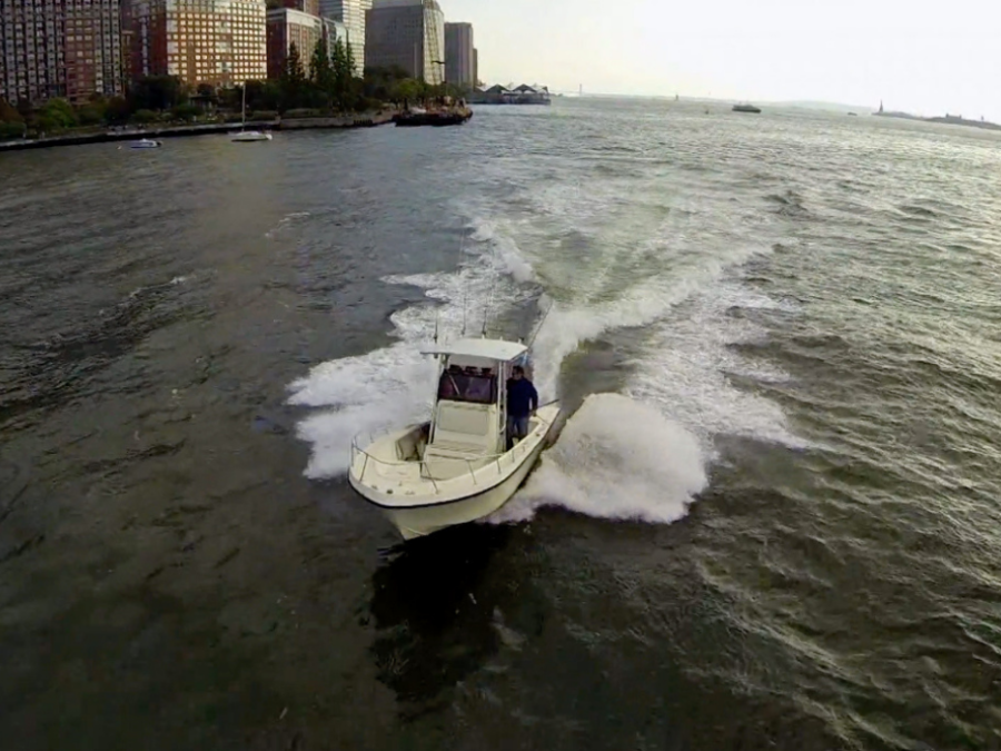 Motorboat speeding on river near city buildings.
