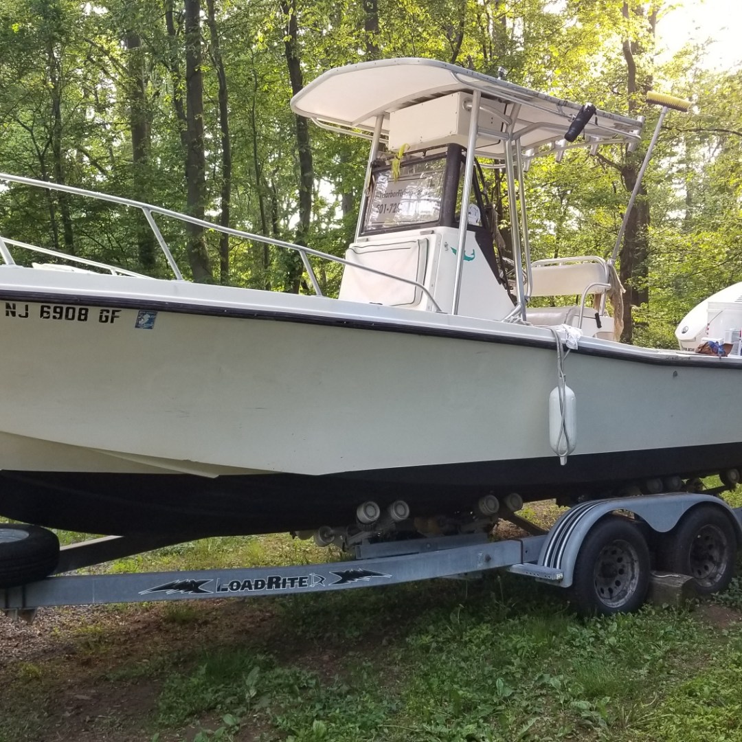 White boat on a trailer in a wooded area